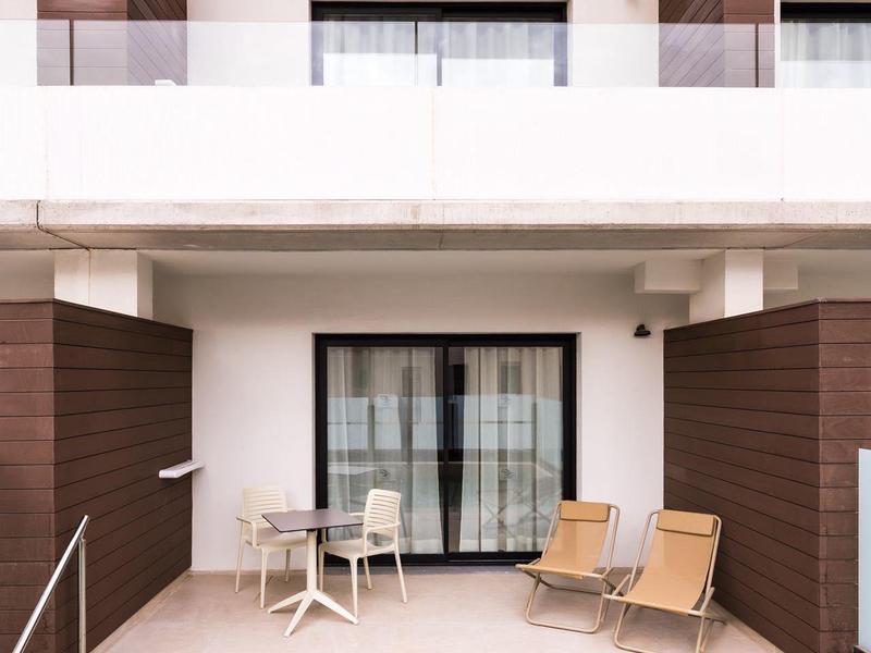 Terrazza di una camera d'hotel moderna con sedie, piccolo tavolo e vista sulla piscina