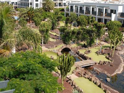 Giardino paesaggistico dell'hotel con piante esotiche, palme e sentieri lungo un corso d'acqua.