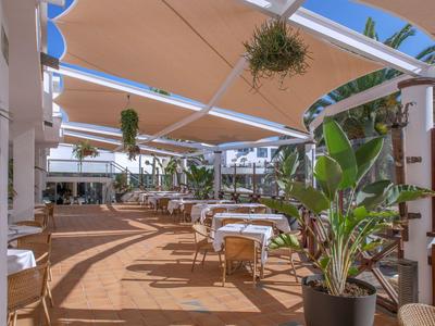 Offener Terrassenbereich eines Restaurants mit Sonnensegeln und dekorativen Pflanzen.