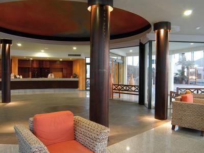 Spaziosa hall dell'hotel con grandi colonne, comode poltrone e banco reception.