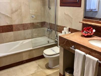 Bagno luminoso con vasca, doccetta, wc e lavabo con specchio.