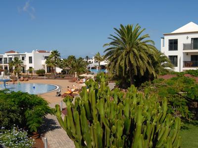 Complesso alberghiero con piscina, palme e ospiti in una giornata di sole