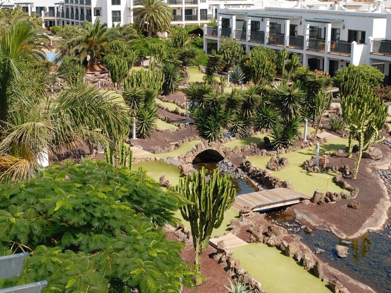 Giardino paesaggistico dell'hotel con piante esotiche, palme e sentieri lungo un corso d'acqua.