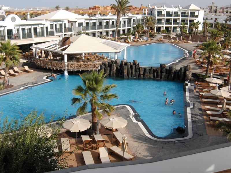 Complesso alberghiero con edifici bianchi e giardini tropicali rigogliosi sotto un cielo sereno