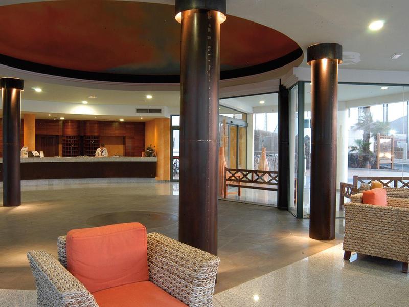 Spaziosa hall dell'hotel con grandi colonne, comode poltrone e banco reception.