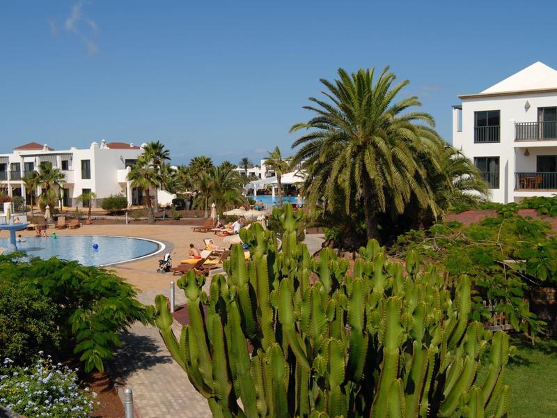 Complesso alberghiero con piscina, palme e ospiti in una giornata di sole