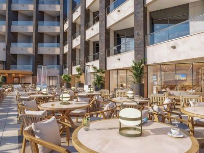 Nowoczesny zewnętrzny obszar hotelu z stołami i krzesłami dla gości do jedzenia i relaksu.