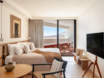 Modern ingerichte hotelkamer met bed en balkon met zitgedeelte.