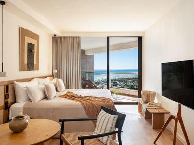 Lichte hotelkamer met zeezicht, comfortabel bed en modern interieur.