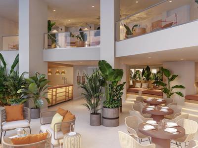 Lichte, moderne hotel lounge met zithoeken, planten en een interieur met twee verdiepingen.