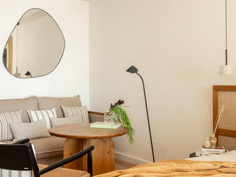 Gezellige woonkamer met beige bank, ronde houten tafel en moderne vloerlamp.