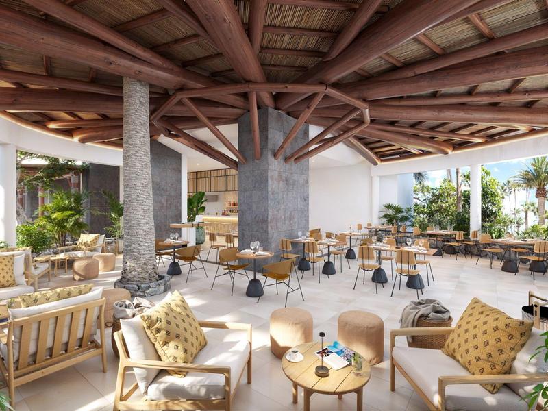 Open lounge met houten dak, comfortabele stoelen, tafels, omgeven door planten.