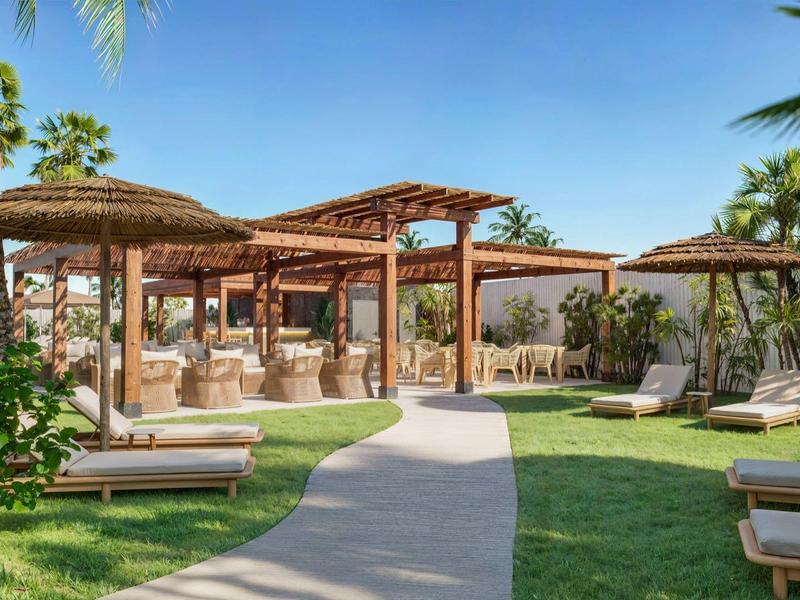 Gebogen pad naar meerdere open houten paviljoens met ligbedden in tropische tuin.