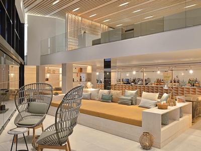 Área moderna del vestíbulo del hotel con asientos cómodos y diseño elegante en colores neutros.