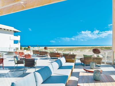 Terraza moderna con asientos cómodos y vista al mar bajo un cielo despejado.