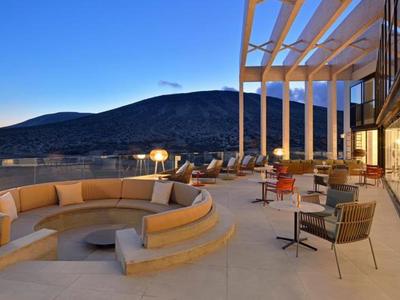 Terrasse avec assise circulaire surplombant des collines au coucher du soleil.