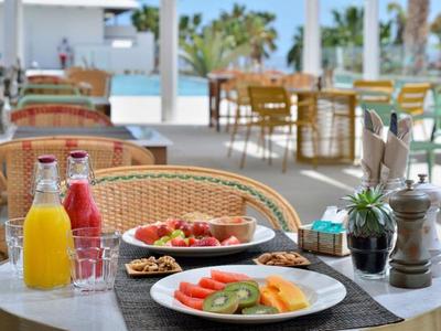 Frühstückstisch im Freien mit Säften, Obst und Müsli in einer Hotelterrasse.