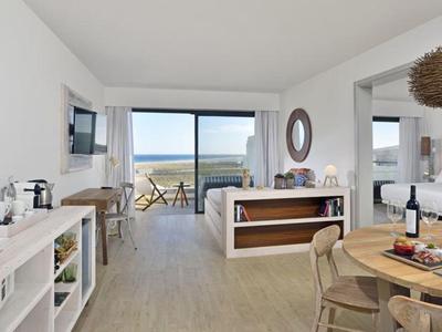 Chambre d'hôtel lumineuse avec vue sur la mer et balcon sur la plage.