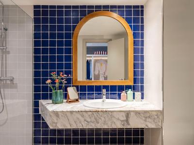 Bagno moderno con parete piastrellata blu e piano lavabo in marmo in un hotel.