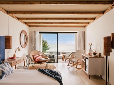 Soggiorno luminoso con soffitto in legno, mobili moderni e ampia vetrata con vista mare.