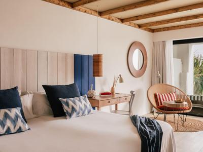 Modern eingerichtetes Hotelzimmer mit Doppelbett, Sitzbereich und Blick auf Balkon.