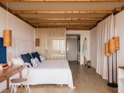 Modernes Hotelzimmer mit Doppelbett, Holzbalken und warmen Lampen.