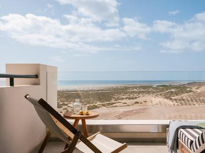 Terrasse mit Liegestuhl und Meerblick an einem sonnigen Strandhotel.