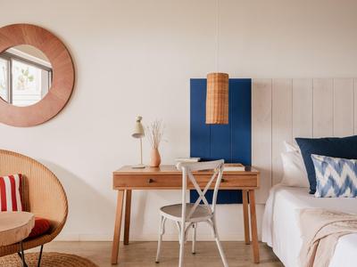 Camera d'albergo accogliente con scrivania, sedia, letto e specchio decorativo sulla parete.