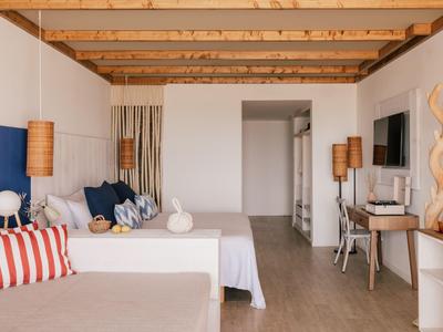 Helle Hotelzimmer mit zwei Betten, Holzdecke und modernen Lampen im klaren Design.
