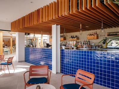 Moderner Hotelbarbereich mit blauen Fliesen und stilvollen Sitzgelegenheiten in warmem Licht.