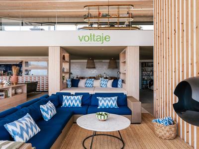 Modernes Hotelzimmer mit blauen Sofas, Holzelementen und gemütlicher Sitzecke.