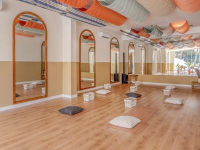 Heller, geräumiger Raum mit Holzboden, Kissen und Spiegeln, ideal für Yoga oder Meditation im Hotel.