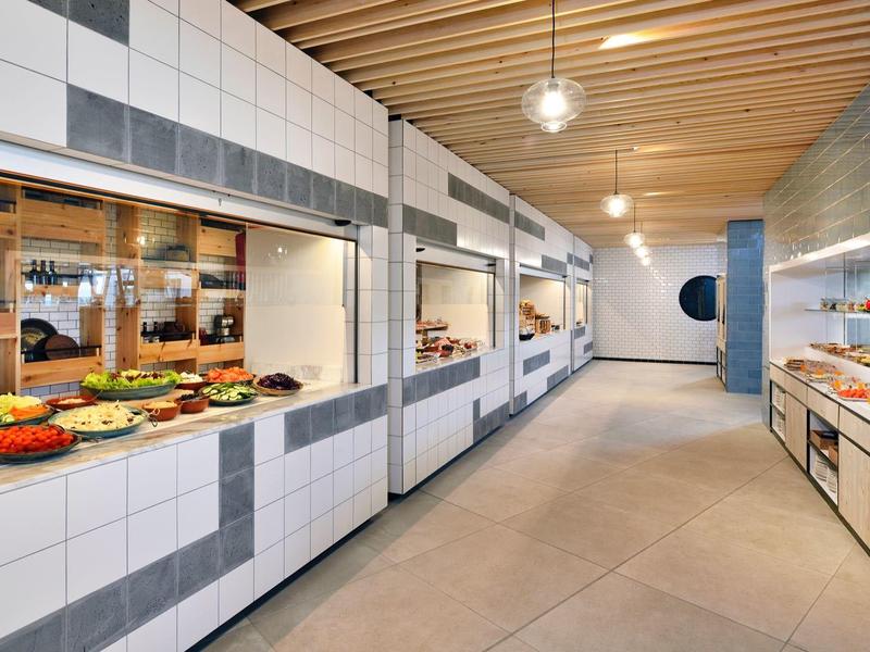 Área de buffet moderna con verduras y ensaladas en un restaurante del hotel con techo de madera clara.