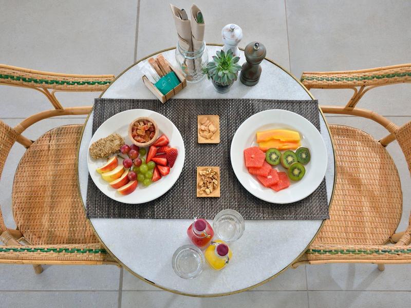 Dos platos con frutas y nueces en una mesa redonda con dos sillas en un área al aire libre.
