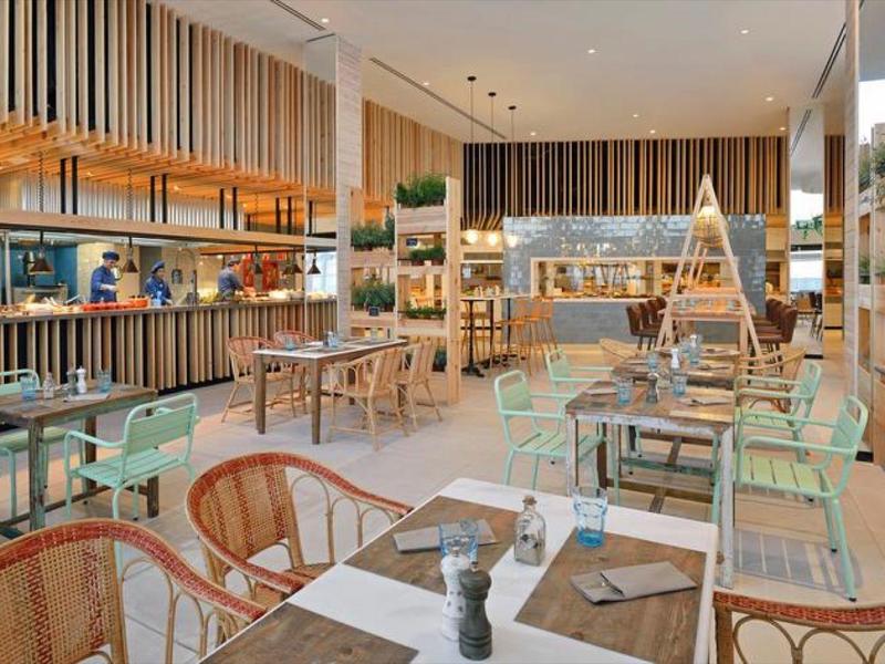 Restaurante moderno y luminoso con muebles de madera y plantas, listo para huéspedes.