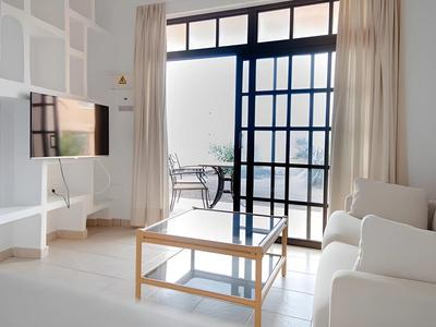 Bright living room with white furniture, large window, and balcony seating.