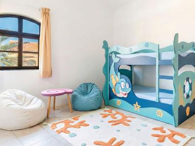Kinderschlafzimmer mit Etagenbett, Sitzsäcken, kleinem Tisch und Teppich unter einem Fenster