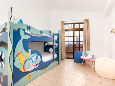 Children's bedroom with nautical bunk bed and cozy bean bags in front of window with curtains.