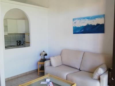 Bright living room with white sofa, glass coffee table, and wall art above the sofa.