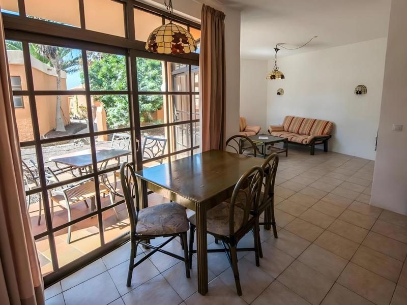 Dining table with four chairs in a bright room with access to a terrace.