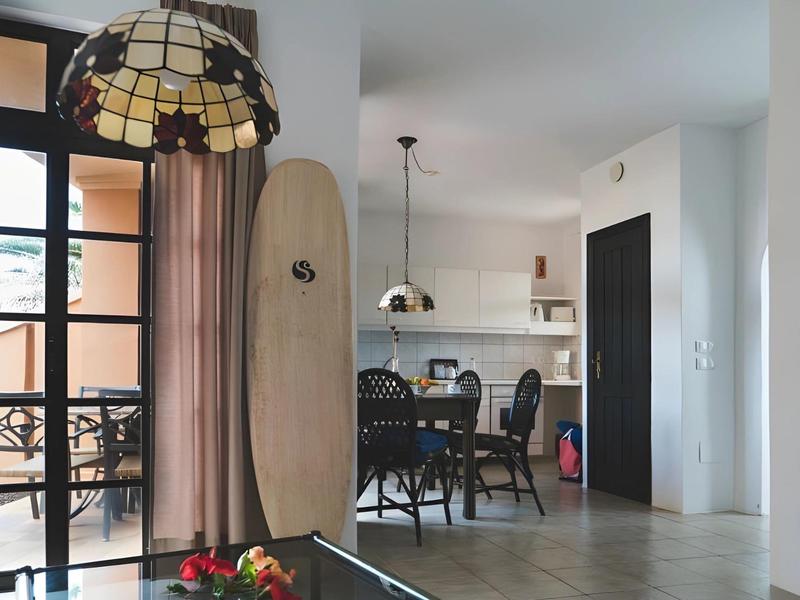 Modern dining area with surfboard decor and view of terrace through glass door