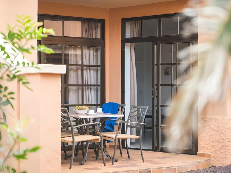 Terrace with table and chairs outside a hotel room with balcony doors.