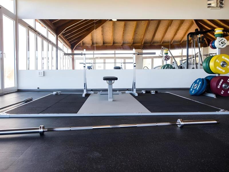 Modern gym weightlifting platform with barbell and colorful weight plates.