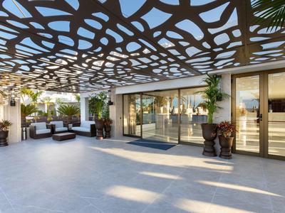 Ingresso moderno della hall dell'hotel con elemento di soffitto decorativo traforato e mobili lounge.