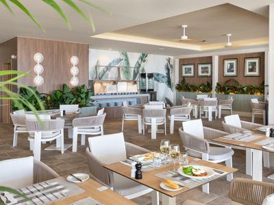 Ristorante moderno dell'hotel con sedie bianche e piante decorative