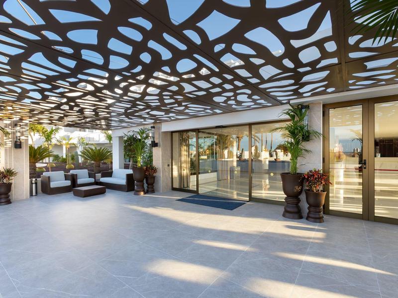 Ingresso moderno della hall dell'hotel con elemento di soffitto decorativo traforato e mobili lounge.