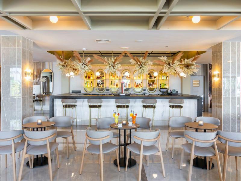 Area bar di un hotel moderno con sedute eleganti e bancone decorativamente illuminato.