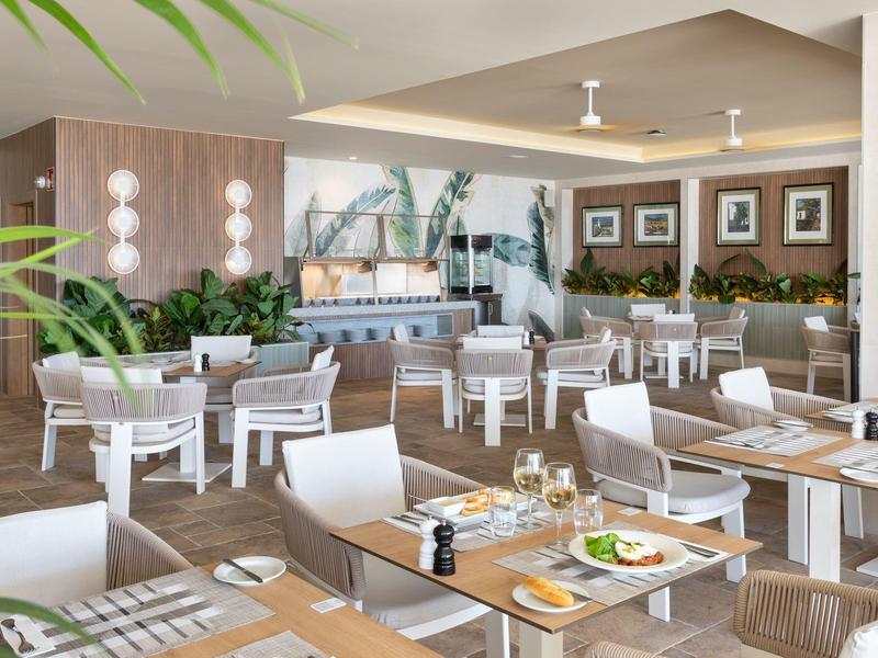 Ristorante moderno dell'hotel con sedie bianche e piante decorative