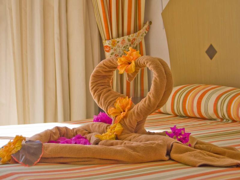 Decorazione di asciugamani a forma di cuore con fiori su un letto in camera d'hotel.