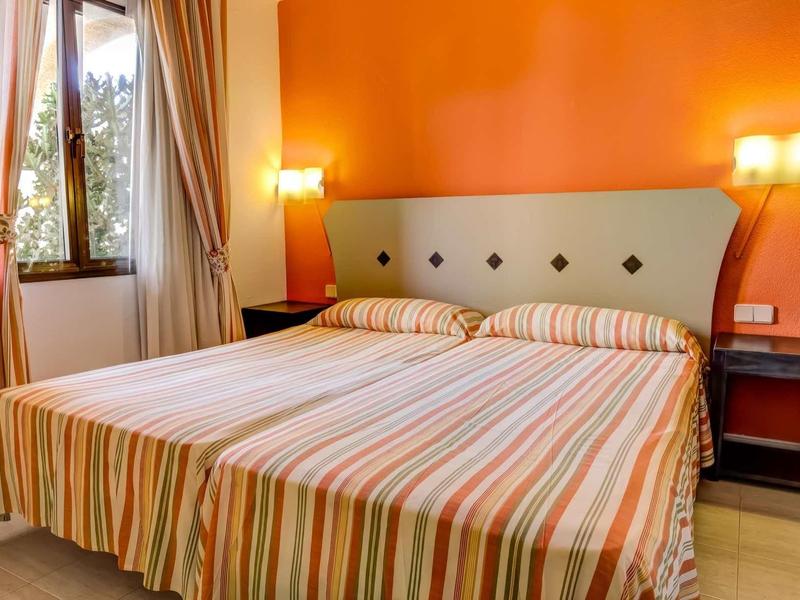 Letto matrimoniale accogliente con copertura a righe in stanza calda arancione.